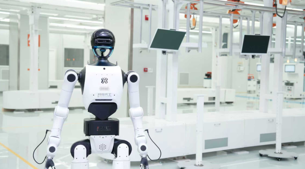 The Tiangong embodied robot standing confidently in the factory setting, displaying its mechanical joints and blue lighting accents.